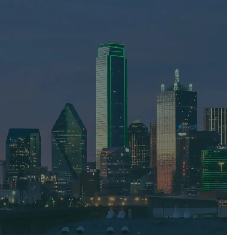 Twilight cityscape with illuminated skyscrapers and distinctive tower.