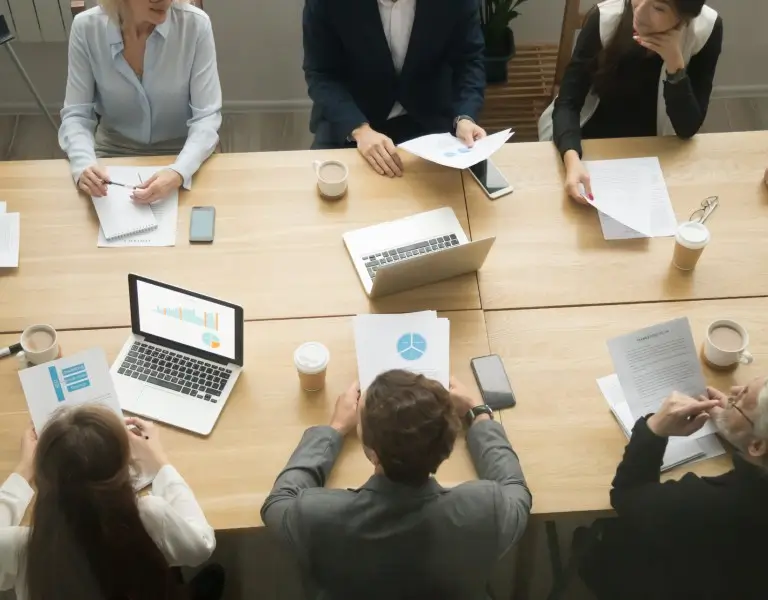 a person sitting at a table with a laptop and papers