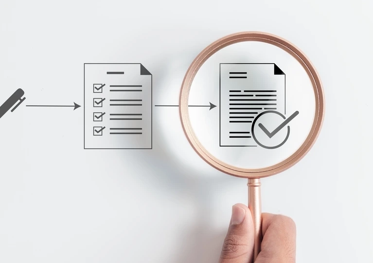 Hand holding a magnifying glass over a checklist, emphasizing the importance of detail in task completion