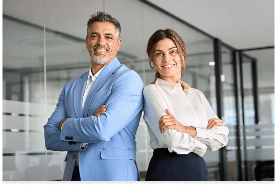 Two professionals standing confidently with arms crossed in a modern office setting, dressed in business attire.