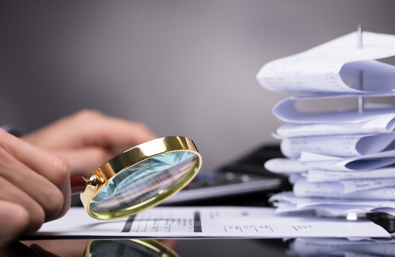 man uses a magnifying glass to look at documents