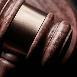 Close-up of a wooden gavel with a shiny metallic band, symbolizing justice and authority in a courtroom setting.
