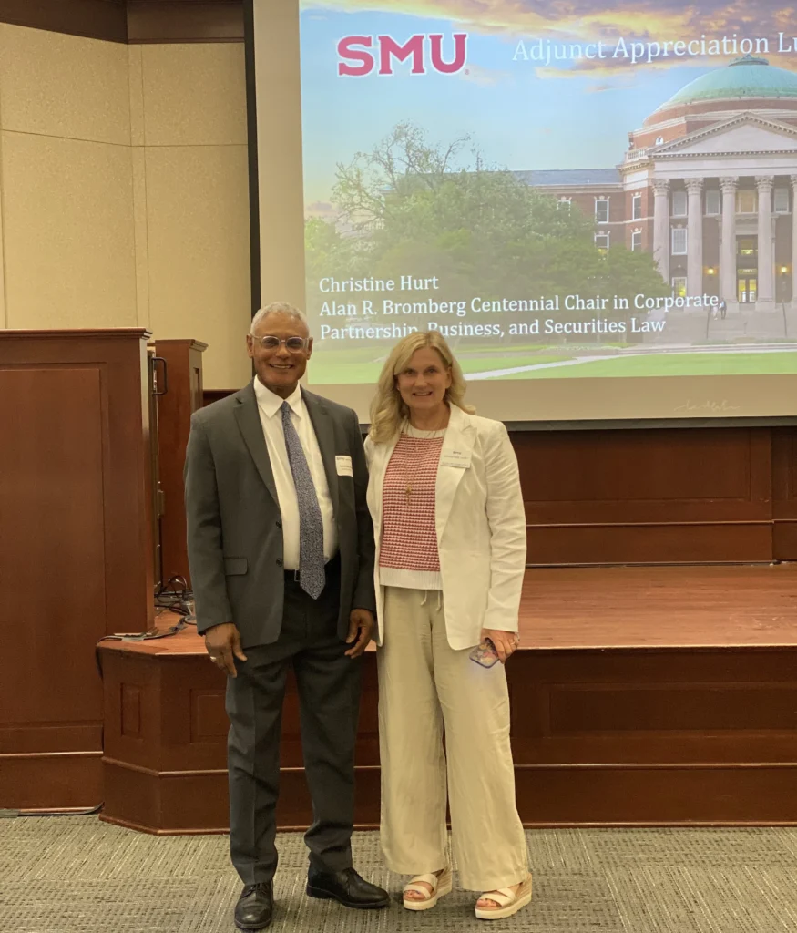 Two professionally dressed individuals standing in front of a presentation screen displaying "SMU Adjunct Appreciation" and academic titles.