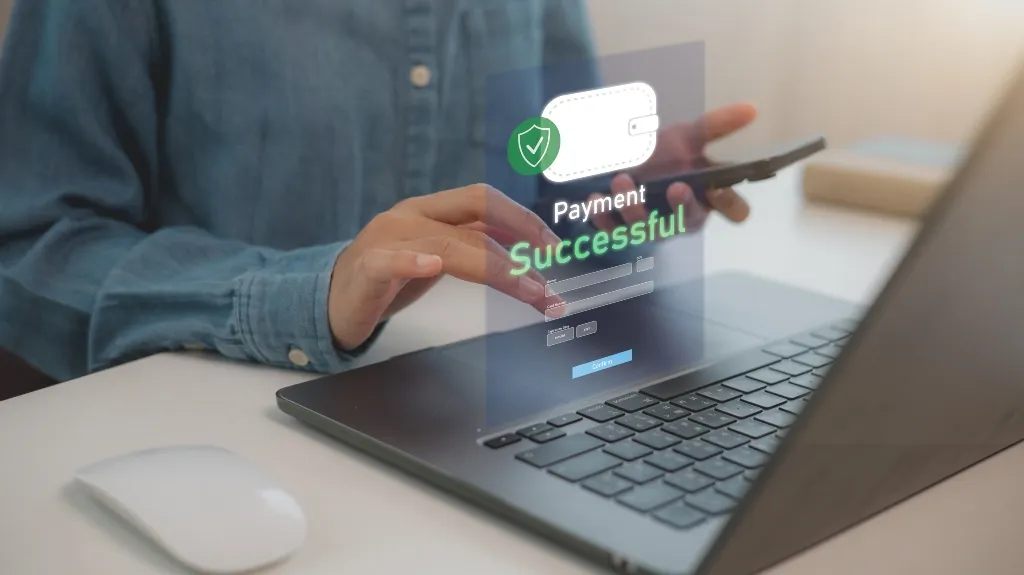 Person using laptop and smartphone with digital "Payment Successful" notification displayed.