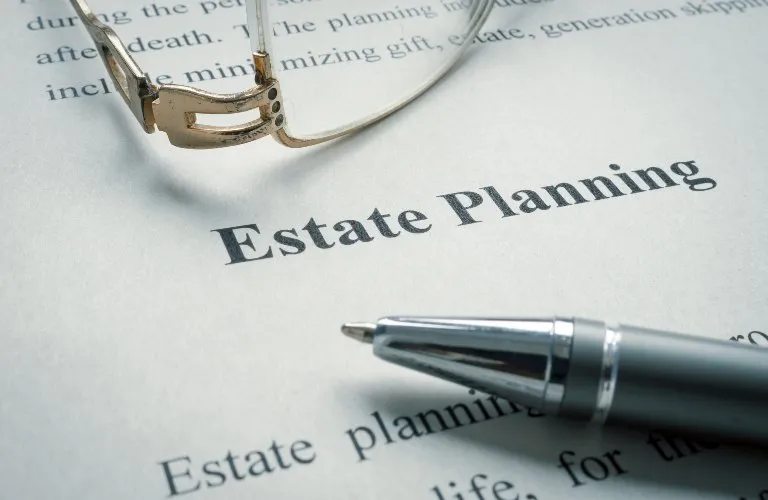 Close-up of a document titled "Estate Planning" with a pen and eyeglasses resting on the paper.