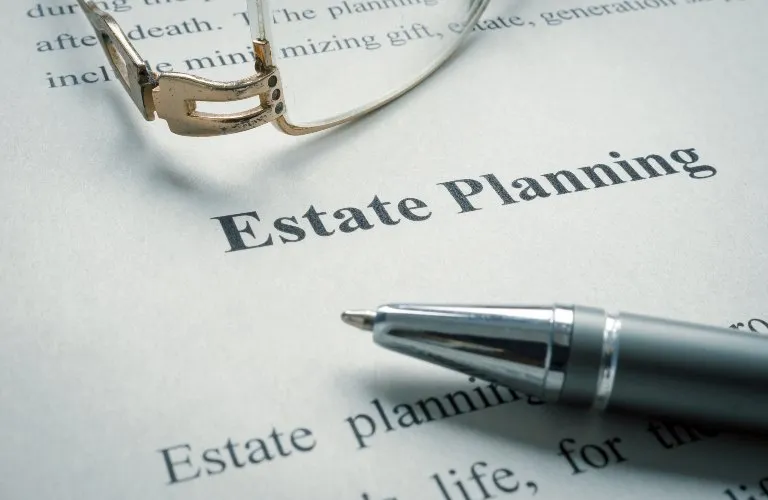 Close-up of a document titled "Estate Planning" with a silver pen and eyeglasses resting on it.